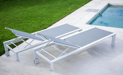 Picture of lounge chairs setting evenly on concrete pool deck